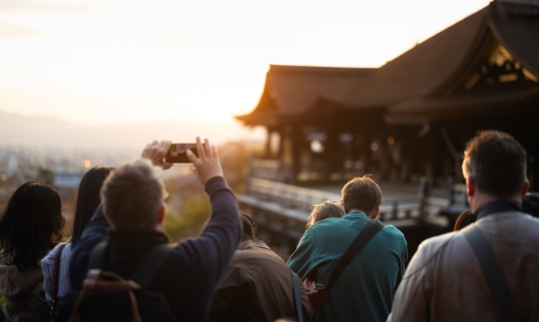 People take photos of a temple at sunset.